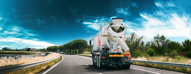 panorama Panoramic View Special Concrete Transport Truck In-transit Mixer Unit In Motion On Country Road, Freeway. Freeway Motorway Highway. Business Drive Transportation And Development Concept - 617388143
