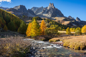 Fototapeta na wymiar Claree Valley in the French Alps with larch trees and Main de Crepin mountain peak. Autumn in Cerces Massif. Hautes Alpes, France
