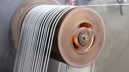Fotobehang Séchage de lanières industrielles sur un rouleau chauffant qui tourne à grande vitesse pour lisser et étirer les fibres. © fred.do.photo