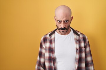 Hispanic man with beard standing over yellow background skeptic and nervous, frowning upset because of problem. negative person.