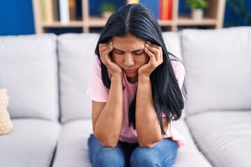 Middle age hispanic woman stressed sitting on sofa at home