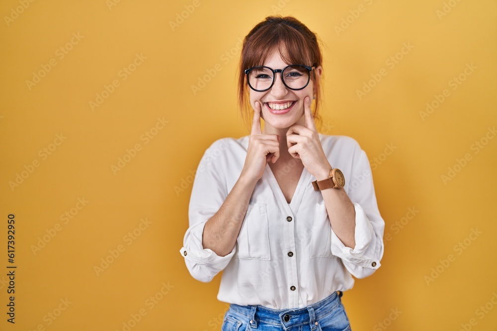 Wall mural young beautiful woman wearing casual shirt over yellow background smiling with open mouth, fingers p