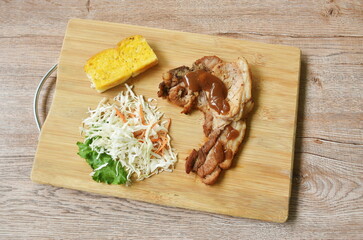 fried chop pork steak with butter garlic bread and salad on cutting board