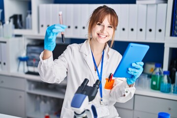 Young woman scientist holding blood analysis and touchpad at laboratory