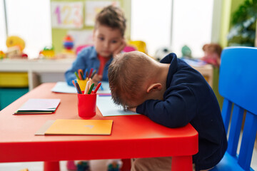 Adorable boys preschool students sitting on table crying at kindergarten