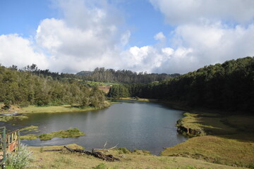 River flowing with green hills and blue sky