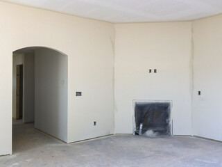Primed walls in new home construction with fireplace and arched door opening