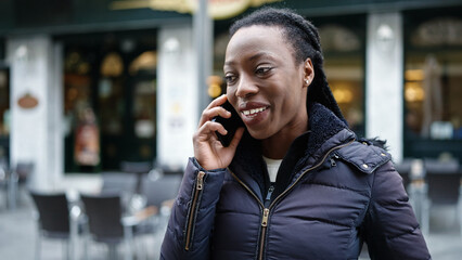 African american woman smiling confident talking on smartphone at coffee shop terrace