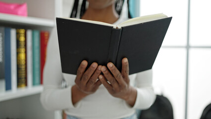 African american woman student reading book standing at university classroom