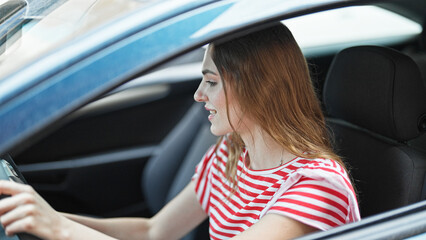 Young blonde woman smiling confident starting car at street