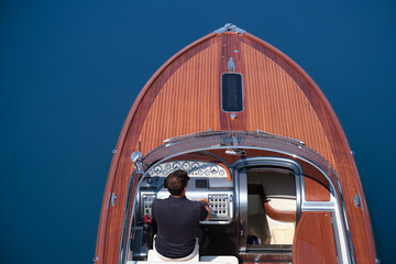 Fashion wooden boat with a man on the water aerial view. Luxury boat on the water. Luxurious big boat for millionaires deck part on blue water top view. - obrazy, fototapety, plakaty
