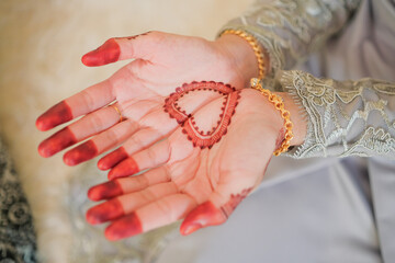 Malay wedding groom bolstering gold ring on bride's finger