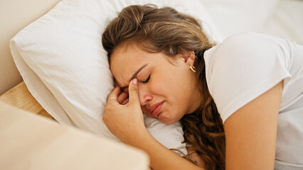 Fototapeta premium Young beautiful hispanic woman lying on bed crying at bedroom