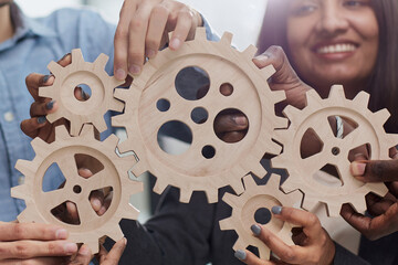 Office worker holding cog wheel as unity and teamwork in corporate workplace concept.