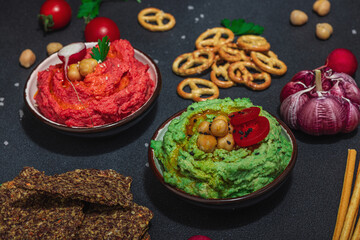 Various hummus dips, fresh vegetables and herbs. Crispy bread snacks, modern vegan healthy food