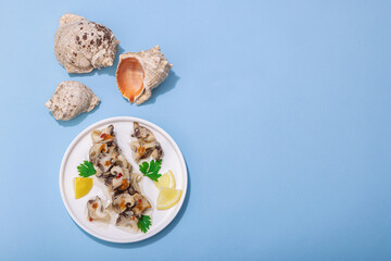 Pickled rapan meat with oil, spices and greens. Healthy seafood rich of omega