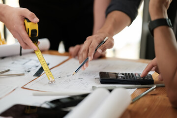 Close up of hand's architects working on blueprints in the office with drawing tools and a blueprint on his desk.