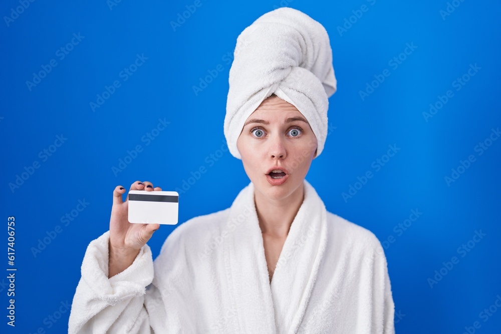 Canvas Prints blonde caucasian woman wearing bathrobe holding credit card scared and amazed with open mouth for su