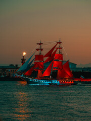Sailing ship with red sails sailing on a surreal blue landscape with a rainbow. Artwork.