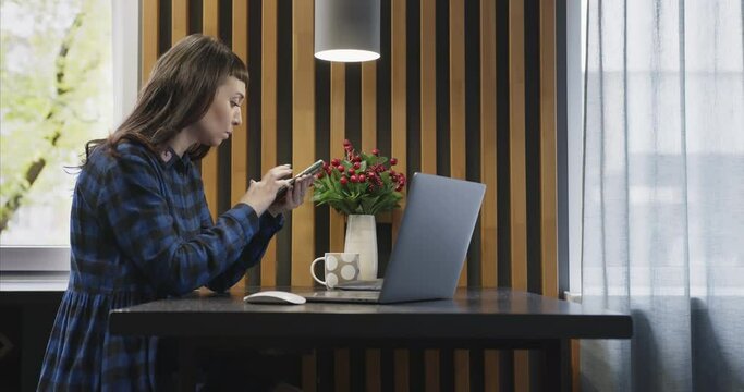 A woman anxiously typing on laptop, calling the bank and checking a credit card