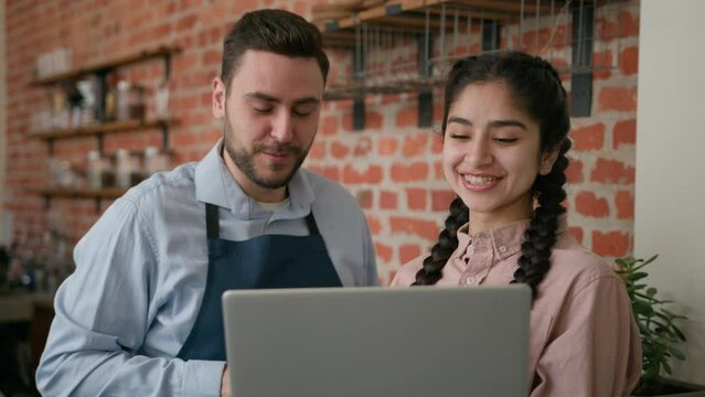 Diverse Smiling Waiter Manager Discussing Working Schedule On Laptop Cafe Employees Man Woman Looking Computer Screen Developing New Work Strategy Talking About Business Plan Restaurant Staff Meeting