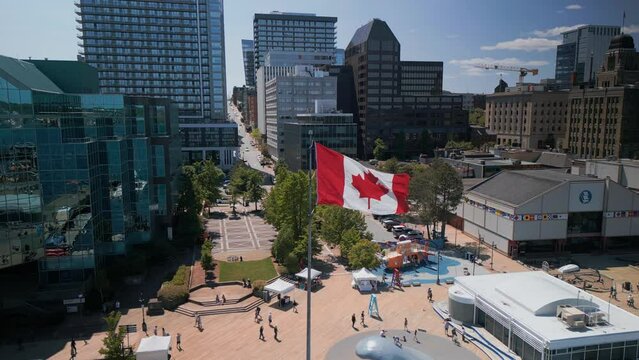 Aerial View of the Canadian Flag Waving in the Wind in the Center of the Modern City of Halifax, Canada. Drone Shot at the Waterfront and Skyscrapers with the Canada Flag in the Center.