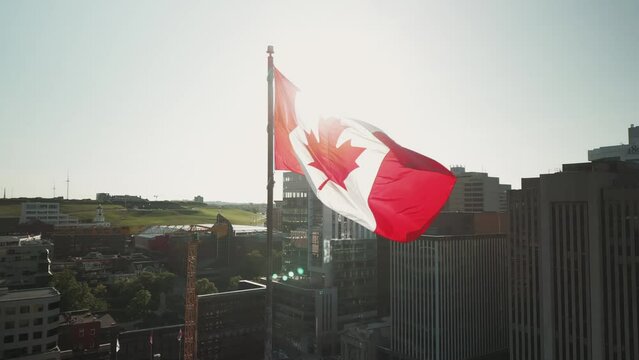 Aerial View of the Canadian Flag Waving in the Wind in the Center of the Modern City of Halifax, Canada. Drone Shot at the Waterfront and Skyscrapers with the Canada Flag in the Center.