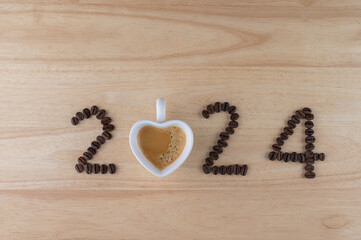 2024 coffee beans and espresso in white cup of heart shape on wooden background, New Year concept
