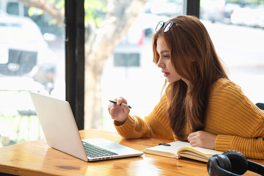 Happy latin girl college student watching distance online learning class, remote university webinar or having talk on laptop video call and use notebook to virtual meeting seminar at home or campus