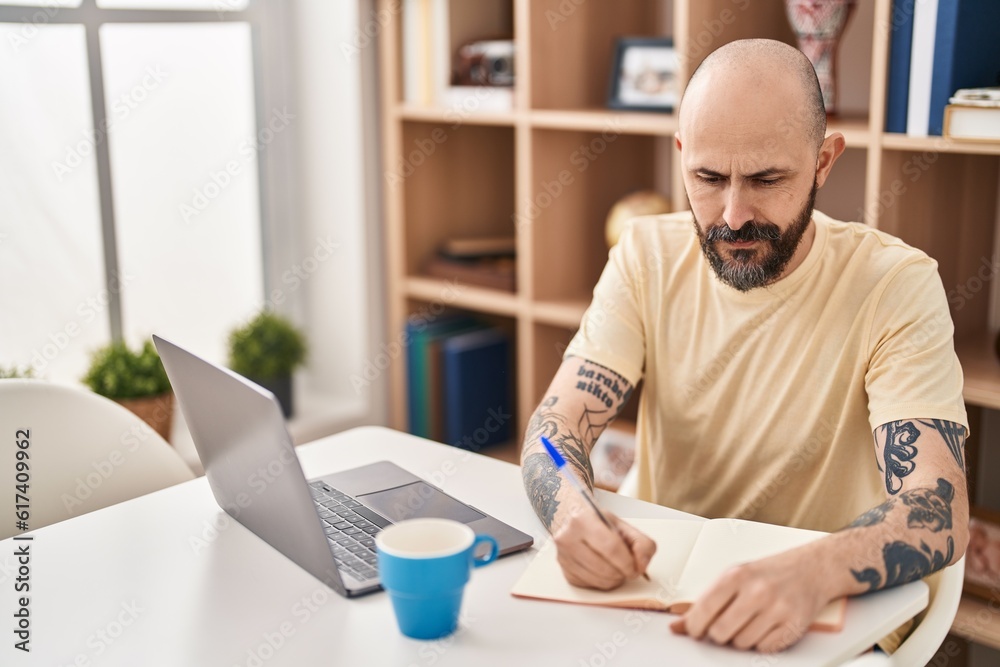 Sticker young bald man sitting on table studying at home