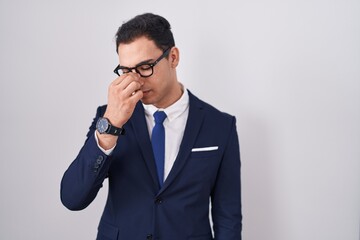 Young hispanic man wearing suit and tie tired rubbing nose and eyes feeling fatigue and headache. stress and frustration concept.