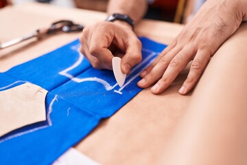 Obraz na płótnie Canvas Young hispanic man tailor make mark on cloth at atelier