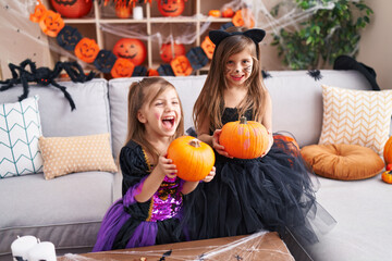 Adorable girls having halloween party holding pumpkin at home