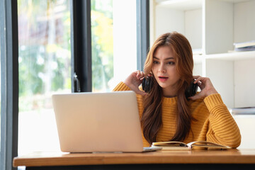 Obraz premium Happy latin girl college student watching distance online learning class, remote university webinar or having talk on laptop video call and use notebook to virtual meeting seminar at home or campus