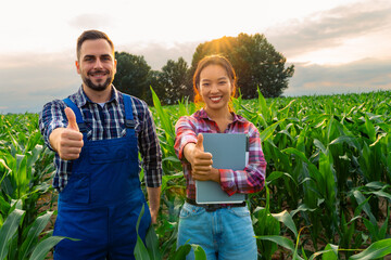 A snapshot of a diverse farming duo standing amidst their cornfield, expressing satisfaction and...
