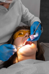Dentist checks for violations in the natural bite after treatment with articulation paper....
