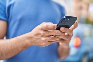 Young latin man using smartphone at street