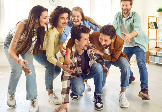 Portrait of a funny young happy overjoyed group of people friends students having fun playing at home and laughing enjoying time together. Party, friendship and team games concept.