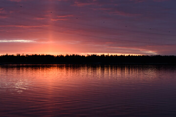 The coastline of islands near Helsinki, at sunset, a red glow in the sky.