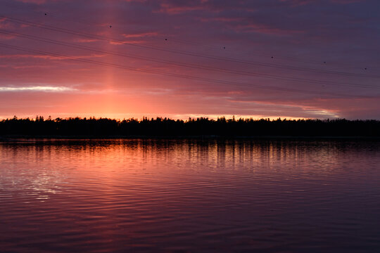 The coastline of islands near Helsinki, at sunset, a red glow in the sky.