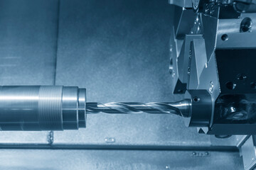The  CNC lathe machine hole cutting the metal shaft parts by drill tool.