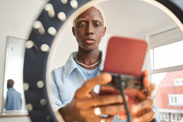 Cropped view of the multiracial blonde blogger man putting mobile phone at tripod