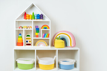 White shelving with rainbow wooden toys and colorful storage baskets. Interior design. Organizing...
