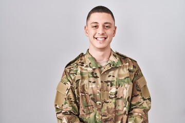 Young man wearing camouflage army uniform with a happy and cool smile on face. lucky person.