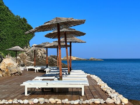 Beach with umbrellas and sunbeds on sea shore in summer.