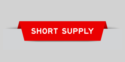 Red color inserted label with word short supply on gray background