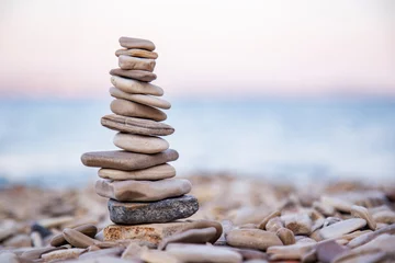 Fotobehang Zen Stenen The pebble tower balances harmony stones on the Aegean sea beach at sunset. Relaxing peaceful spa tranquility concept with copy space for text   © Yelena