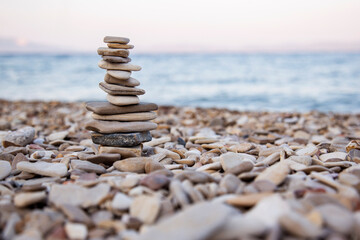 Fototapeta na wymiar A tower from pebbles stones balance on the beach at sunset 