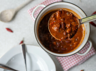 A ladle with delicious bean, beef stew from above