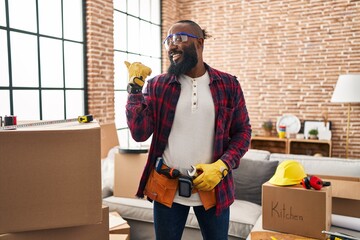 African american man working at home renovation smiling with happy face looking and pointing to the...